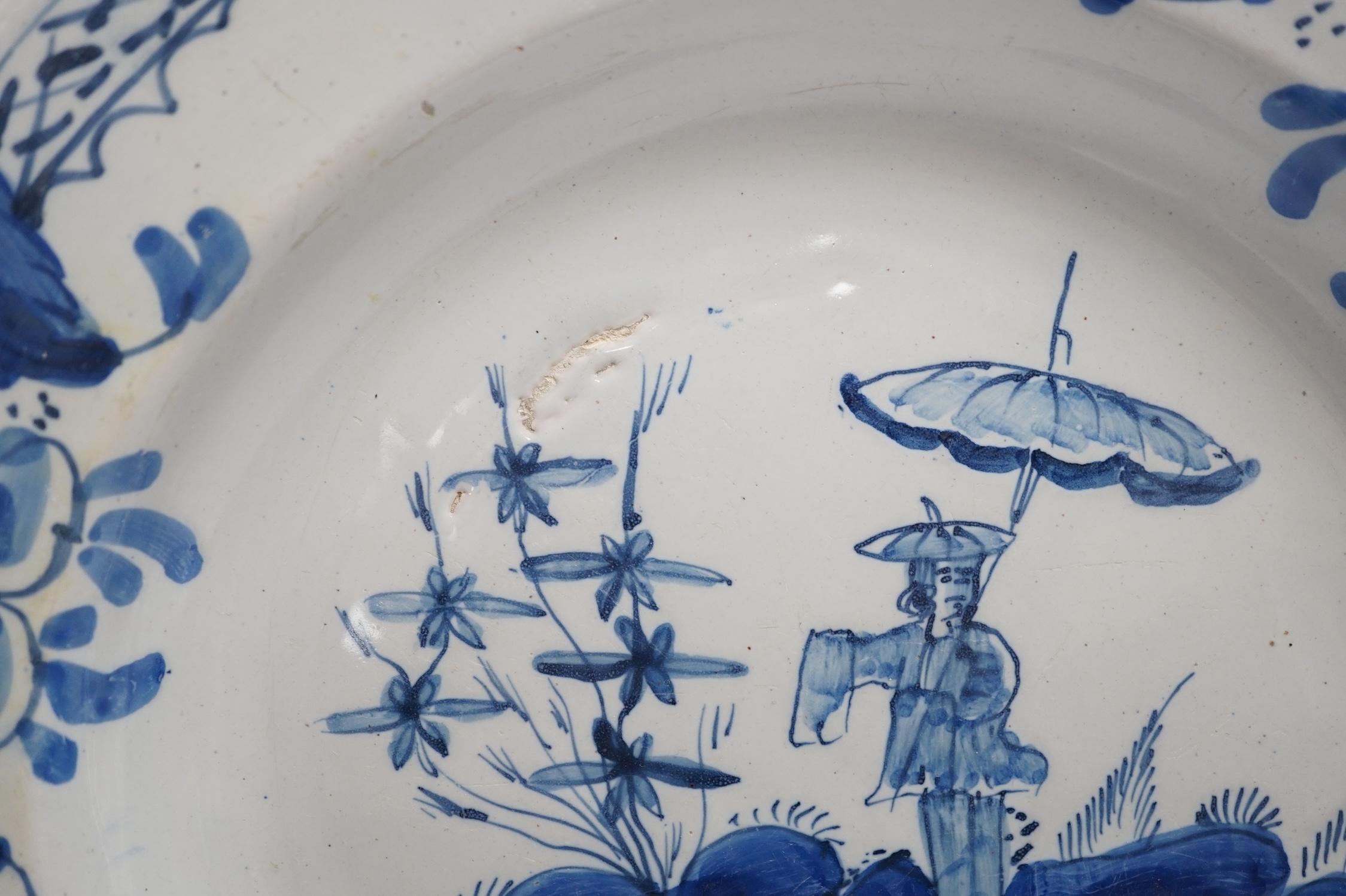 An 18th century Delft dish, decorated with a Chinese scene of a figure with a parasol, diameter 28cm